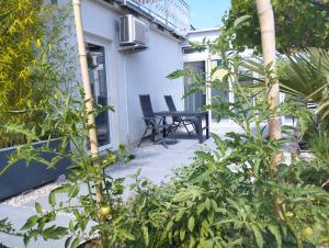 a patio with two chairs and plants in front of a house at Active Apartments Koper in Koper
