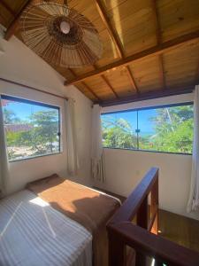 a bedroom with two windows and a bed and a ceiling at Casa Tiririca vista mar in Itacaré