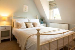 a bedroom with a large bed with white sheets and a window at Windlass Cottage in Lymington