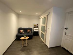 een woonkamer met een zwarte bank en een tafel bij Chambre à Pontarlier in Pontarlier