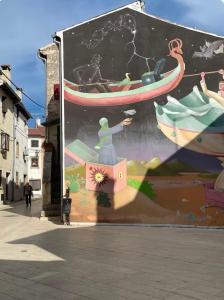 a mural of a person on a boat on a building at Apartment ALMA- Vodnjan- smještaj blizina mora sa besplatnim javnim parkingom in Vodnjan