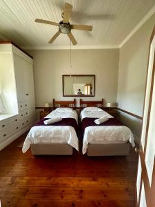 a bedroom with two beds and a ceiling fan at Corner Cottage on Hill in Mossel Bay