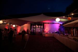 a group of people standing under a tent at night at Denkmalschmiede Höfgen in Grimma