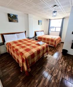 Una habitación de hotel con dos camas y suelos de madera. en Palacio de los Angeles, en San Felipe Hueyotlipan
