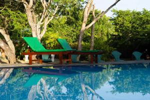 two green chairs sitting next to a swimming pool at Yala Green Eco Lodge in Tissamaharama