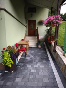 a patio with a wooden table and some flowers at Noclegi pod Witowem in Niedźwiedź