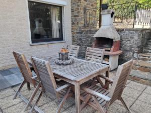 a wooden table and chairs with a brick oven at Balcons de la semois in Vresse-sur-Semois