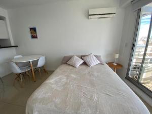 a large bed in a white room with a table at Palermo Soho Luxury Flat with pool and Amenities in Buenos Aires