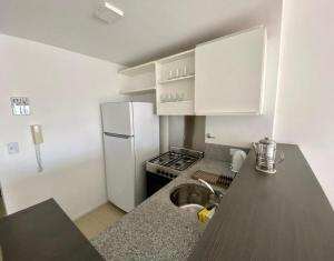 a kitchen with a sink and a white refrigerator at Palermo Soho Luxury Flat with pool and Amenities in Buenos Aires