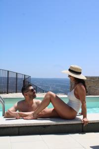a man and a woman sitting next to a swimming pool at Refúgio Muas Nature in Vila Real