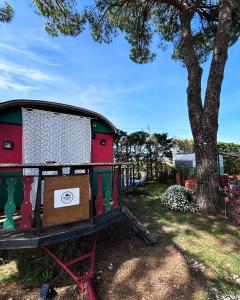 a bed in a trailer next to a tree at Roulotte en Camargue-Hébergement insolite "LA ROULOTTE DE ROMIE", à 15 minutes d'AIGUES-MORTES in Vauvert
