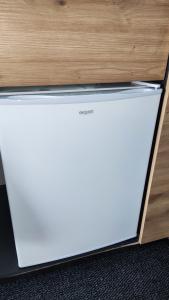 a white refrigerator sitting next to a wooden wall at ÖKO Budget Hausboot Retreat Mondschein in Stralsund
