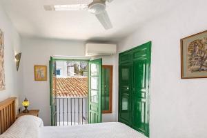 a bedroom with green doors and a window at Casa Sandra in Cómpeta