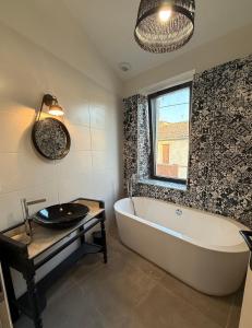 ein Badezimmer mit Badewanne und Waschbecken und einem Fenster in der Unterkunft Maison de bourg au coeur du village médiéval in Saint-Macaire