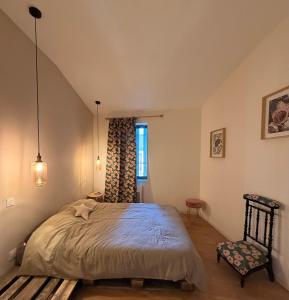 ein Schlafzimmer mit einem großen Bett und einem Stuhl in der Unterkunft Maison de bourg au coeur du village médiéval in Saint-Macaire