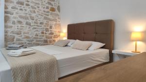 un lit dans une chambre avec un mur en pierre dans l'établissement Heritage Studios Sukosan Center, à Sukošan