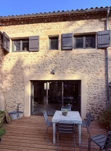 eine Holzterrasse mit einem Tisch und Stühlen vor einem Gebäude in der Unterkunft Maison de bourg au coeur du village médiéval in Saint-Macaire