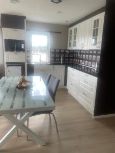 a kitchen with white cabinets and a glass table at Senator appartment with 3 bedrooms near Oslo Airport in Råholt +4 photos