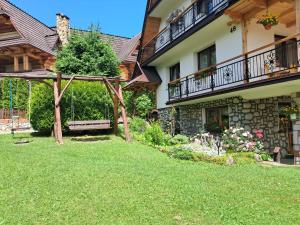a garden in front of a house with a swing at Pokój z balkonem 5 in Kościelisko