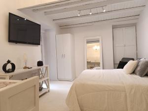 a white bedroom with a bed and a flat screen tv at Modern Studio Historic Center in Quito