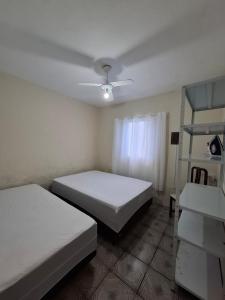 a bedroom with two beds and a ceiling fan at Casa com churrasqueira e piscina in Itanhaém