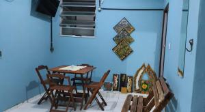 a table and chairs in a room with a blue wall at Hospedagem up home Natureza e Simplicidade in Barra de Guaratiba