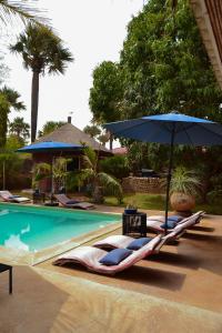 two lounge chairs and an umbrella next to a pool at Keur Palmier Saly in Saly Portudal +43 photos