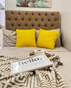 a bed with yellow pillows and a sign on it at Davao Staycation near abreeza and sm lanang in Davao City