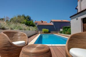 a swimming pool with wicker chairs next to a house at Villa Onorina in Pomer
