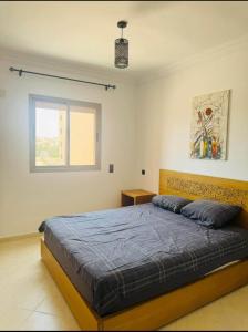 a bedroom with a bed with a blue comforter and a window at Appartement familial a les portes de gueliz in Marrakech