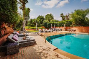 a swimming pool with chairs and a couch next to it at La Villa Wassim in Marrakesh