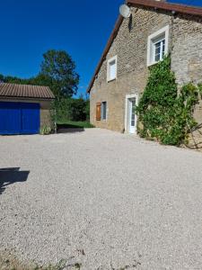 an empty driveway in front of a stone house at la maison bleue in Marcilly-Ogny