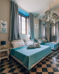 two beds in a bedroom with blue curtains at Palazzo Isabella residenza storica in Borgo San Giacomo in Borgo San Giacomo
