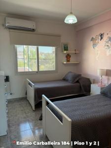 a bedroom with two beds and a window at Departamentos Rufino in Rufino