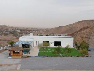 a white building with a green lawn in front of it at Dirat Al-Ghizal 1 in Ras al Khaimah