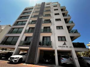 a tall white building with cars parked in a parking lot at Kyrenia Central Kaşkar region 2 bedroom residence in Prodhromi