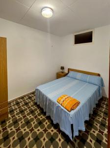 a bedroom with a bed with an orange pillow on it at La Caseta del Port in L'Ametlla de Mar
