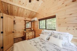 Un dormitorio con una cama en una cabaña de madera. en PineHaus - Brand New Log Cabin at Harvard Brook, en Lincoln