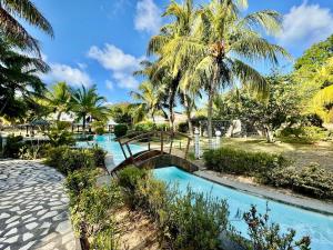a bridge over a swimming pool with palm trees at Beach cozy Studio in Bain Boeuf