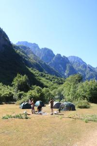 a group of people standing in a field with tents at North wild camping in Shkodër