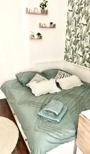 a bed with green sheets and pillows on it at Nice studio with a terrace in Levallois-Perret