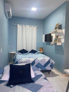 two beds in a bedroom with blue walls at Chale Vista ao Mar Blue in Caucaia