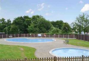 two pools in a yard with a fence at The Chalet in Stalham