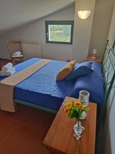 a bedroom with a blue bed and a table with flowers at Giardino degli ulivi in Carbognano