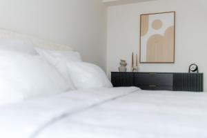 a bed with white sheets and a picture on the wall at R&M Residence in Pécs +15 photos