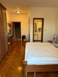 a bedroom with a white bed and a wooden floor at Melija Apartment in Orebić