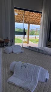 een slaapkamer met een bed met handdoeken erop bij Pousada Pé da Serra - São Thomé das Letras in São Thomé das Letras