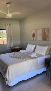 een groot bed met witte lakens en kussens in een slaapkamer bij Pousada Pé da Serra - São Thomé das Letras in São Thomé das Letras