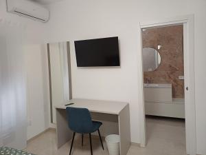 a white room with a desk and a tv on a wall at Le stanze di Anna in Grottole