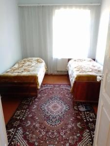 deux lits dans une chambre avec un tapis et une fenêtre dans l'établissement City Escape, à Gyumri